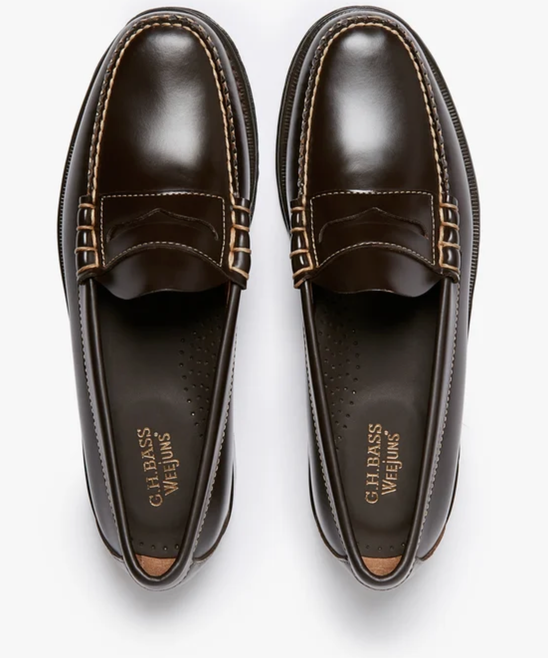 A pair of dark brown leather penny loafers with gold-tone metal eyelets and contrast stitching, shown from a top-down view on a white background. The brand name 'G.